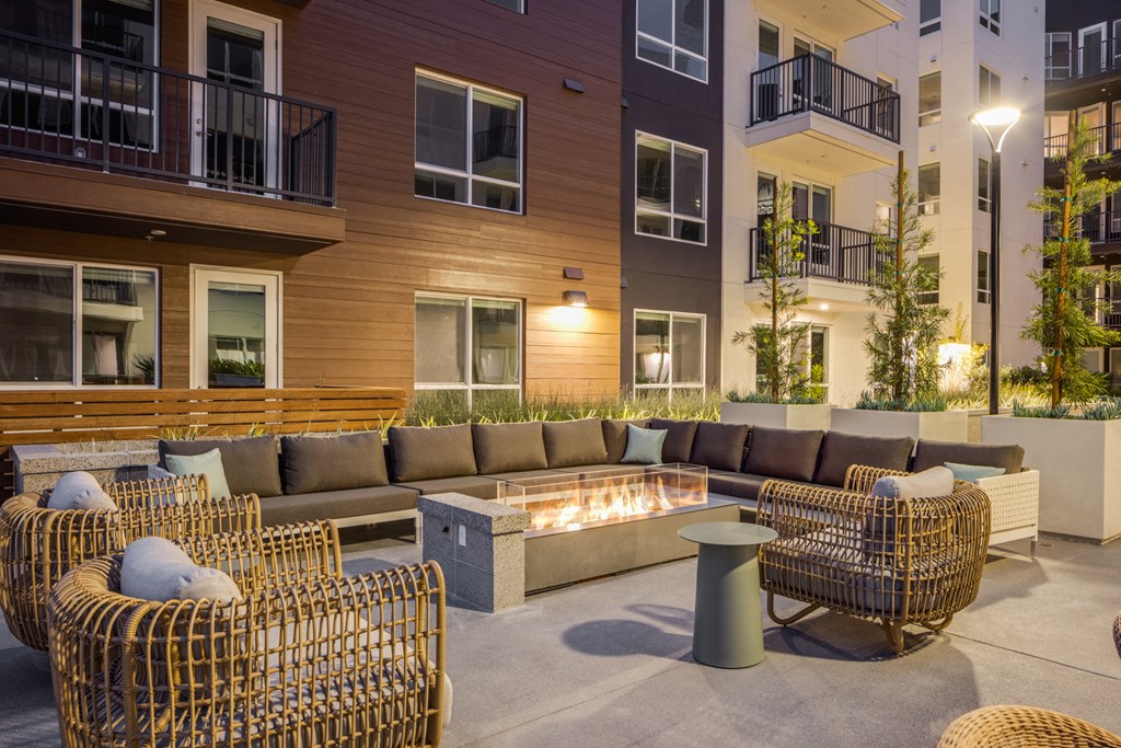 a lounge area with couches and chairs around a fire pit