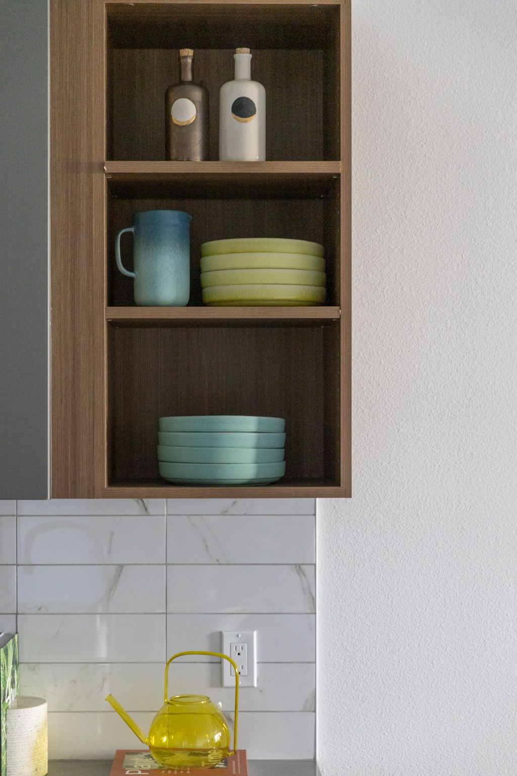 a cupboard with bowls and plates on top of a white kitchen counter