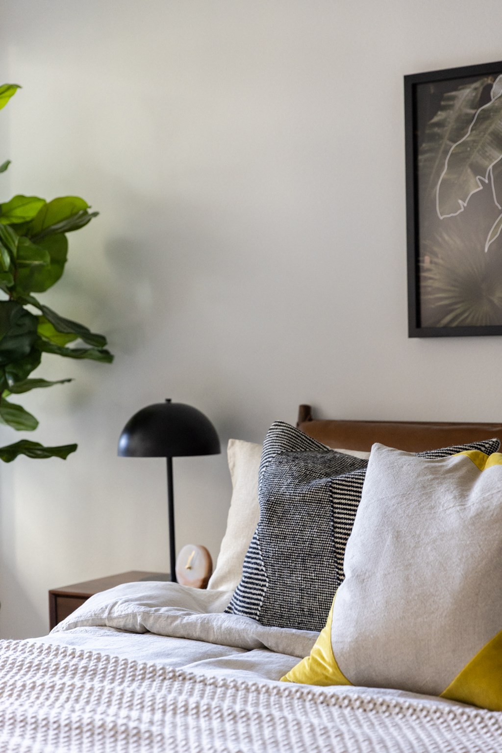a bedroom with a bed with pillows and a black lamp