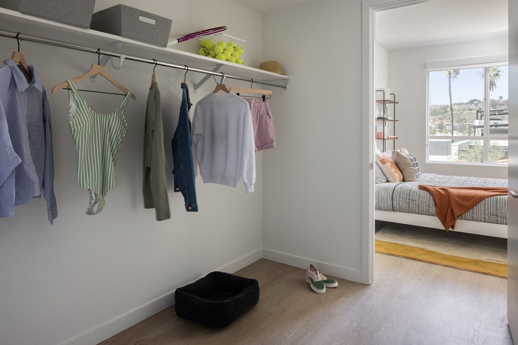 a closet with clothes hanging on a rail in a room with a bed