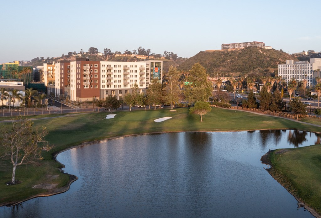 a golf course next to a lake with a city in the background