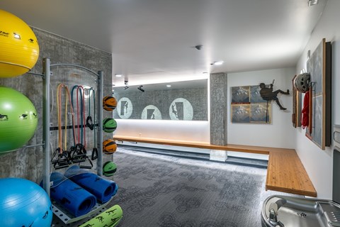 A gym with a variety of equipment including a bench, a ball, and a rack of resistance bands.