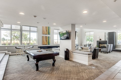 A billiard table is in the middle of a spacious room with a couch and a television.