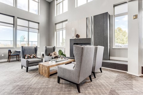 A modern living room with grey chairs and a wooden coffee table.