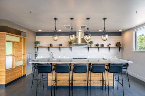 A modern kitchen with a long white island and black barstools.