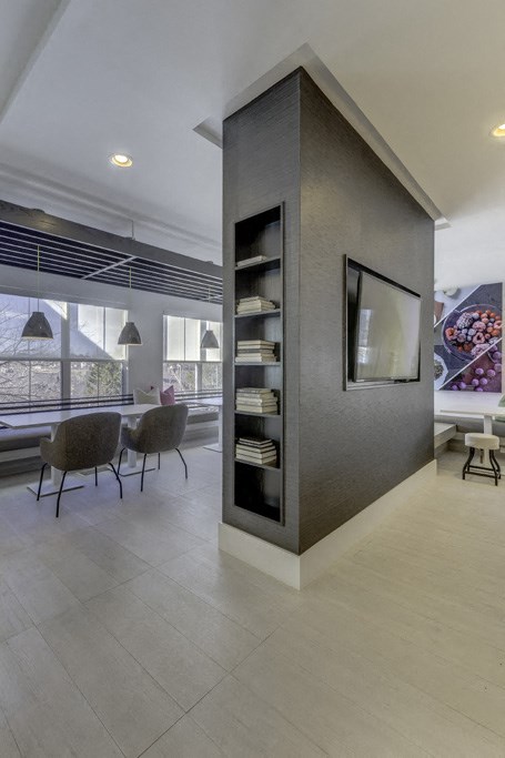 the living room has a large wall with a tv and some chairs