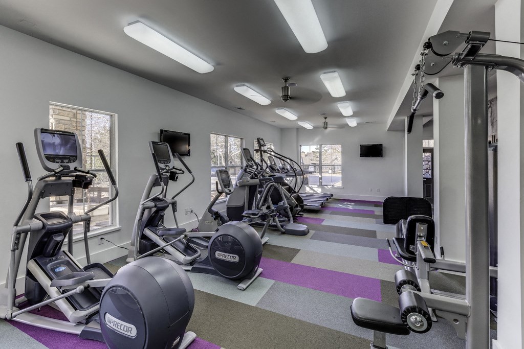 a gym with cardio machines and weights on the floor
