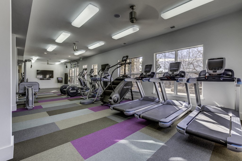 a gym with cardio equipment on the floor and windows