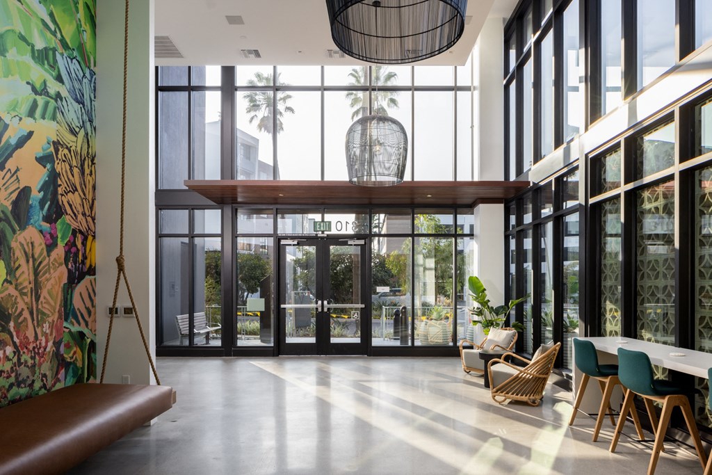 the lobby of a building with large glass windows and a table and chairs