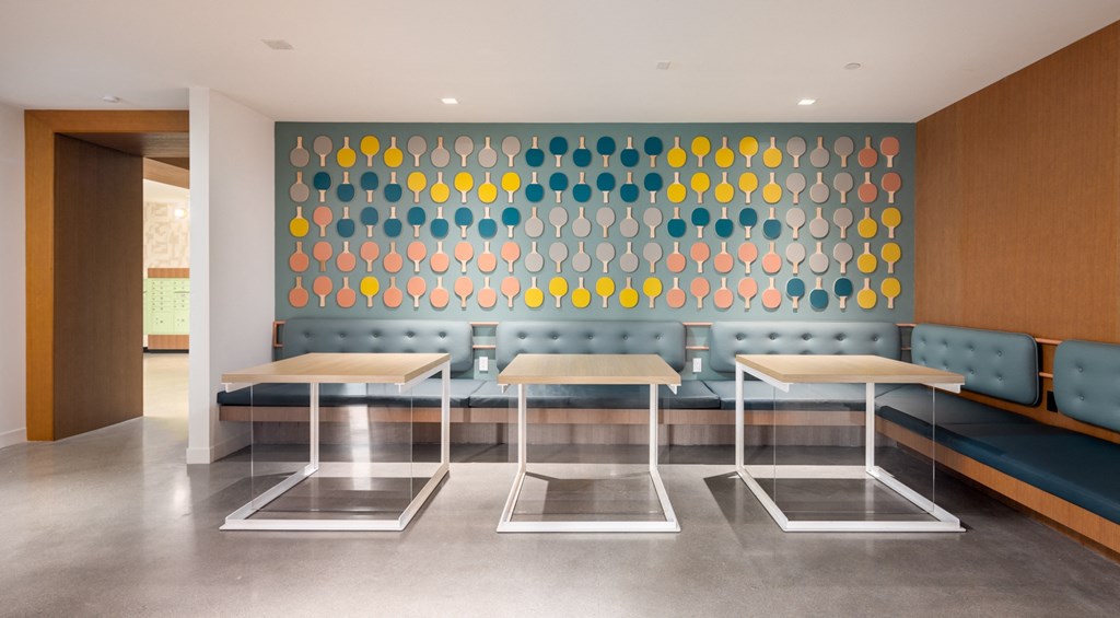 a restaurant with tables and benches and a colorful wall with circles