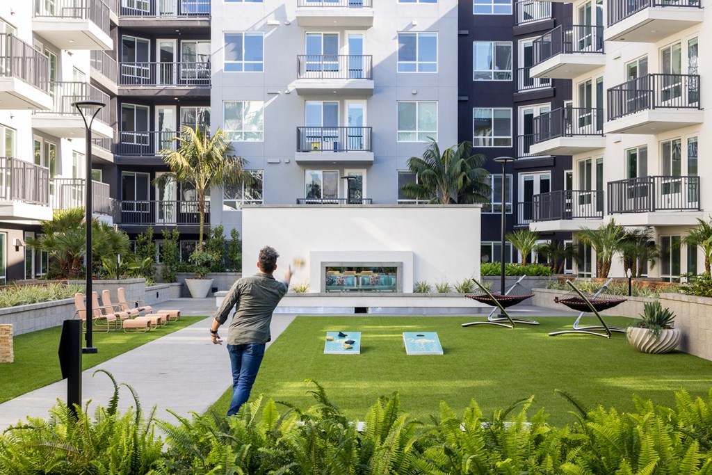 a man standing on a lawn in front of an apartment building