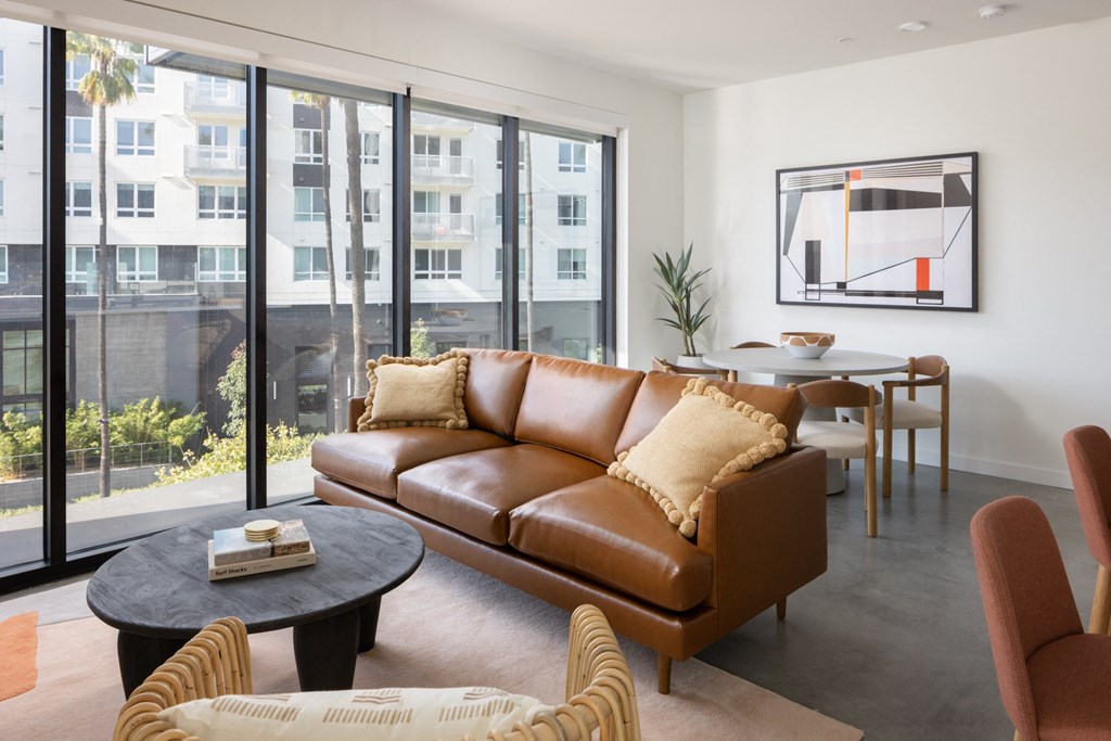 a living room with a brown leather couch and a table with chairs