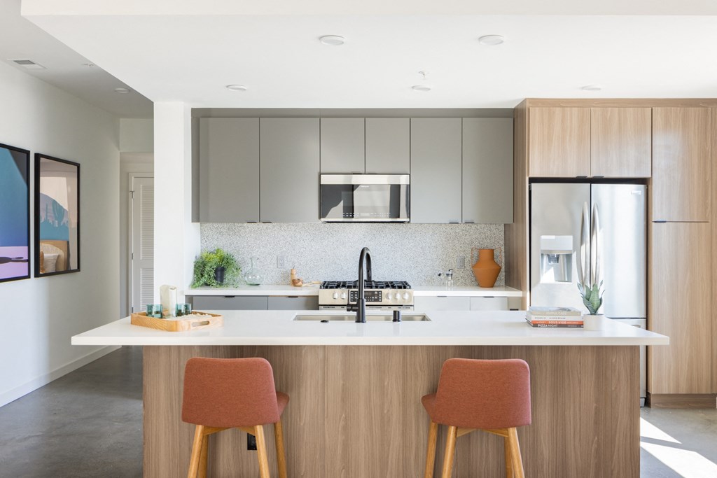 a kitchen with white cabinets and a white counter top with two orange chairs