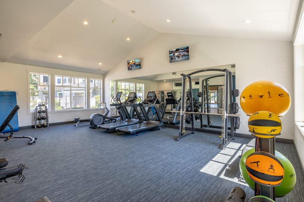 a spacious fitness room with cardio equipment and a flat screen tv
