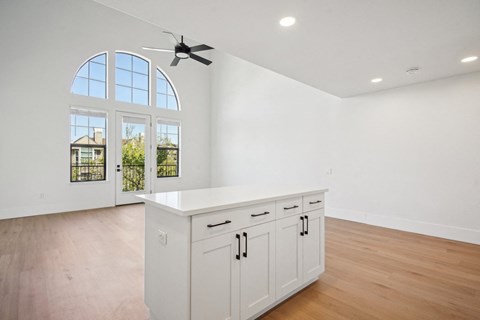 A kitchen with white cabinets and a fan on the ceiling.