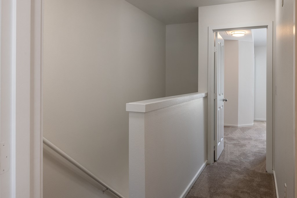 a hallway in a home with white walls and a beige carpet