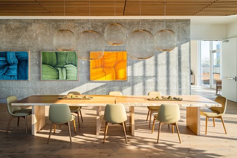 a dining room with a long table and chairs and artwork on the wall