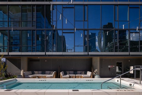 the pool at the top of a building next to a glass facade