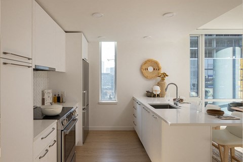 A modern kitchen with white cabinets and a wooden floor.