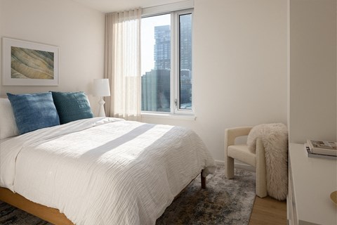 A bedroom with a large bed and a chair.