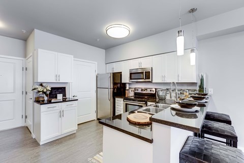 A kitchen with white cabinets and a black bench.