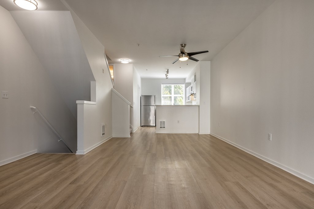 an empty living room with hardwood floors and a ceiling fan