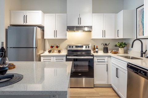 an open kitchen with stainless steel appliances and white cabinets