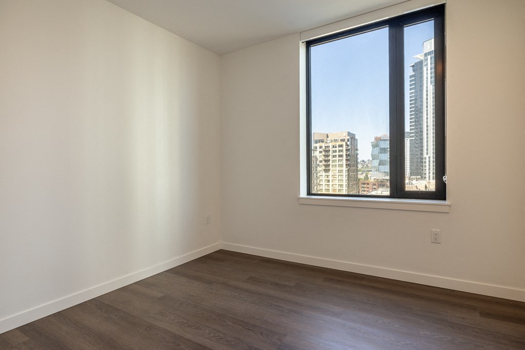 a bedroom with a large window and hardwood floors