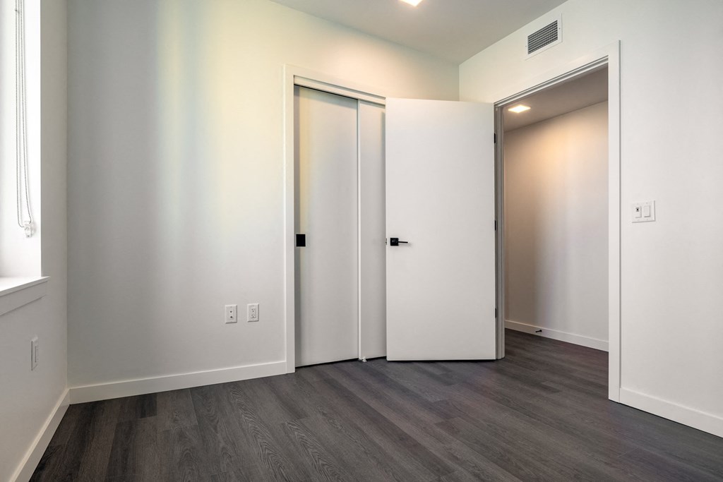 a bedroom with white walls and hardwood floors