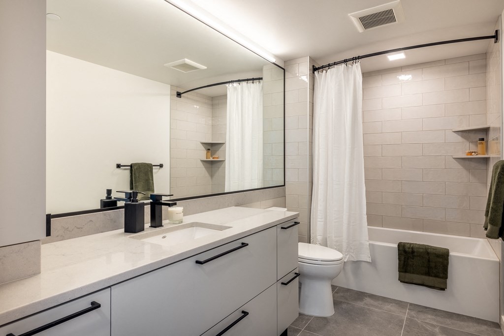 a bathroom with a white toilet and a white tub with a shower curtain