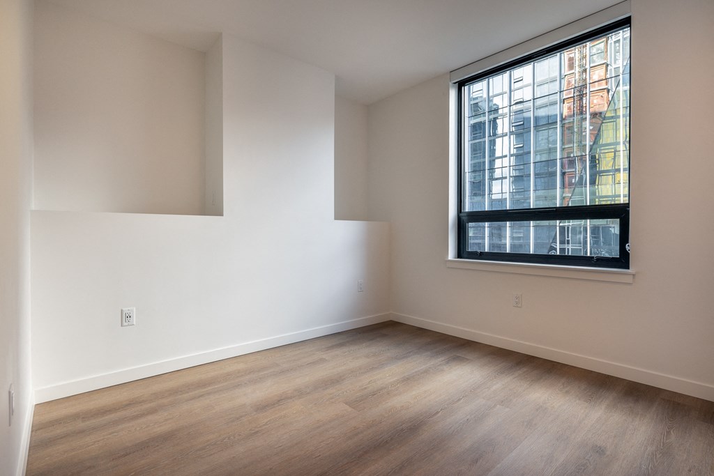 a bedroom with hardwood floors and a large window