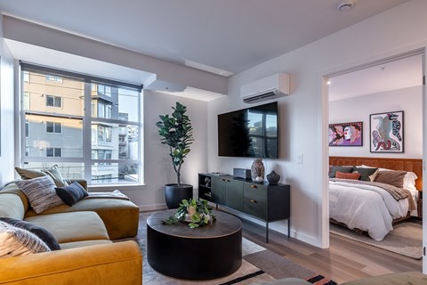 A living room with a yellow couch and a black coffee table.