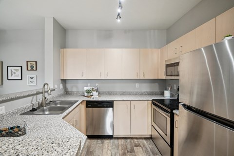 A modern kitchen with a stainless steel refrigerator and wooden cabinets.