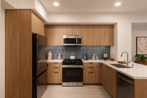 A modern kitchen with wooden cabinets and a black stove top oven.