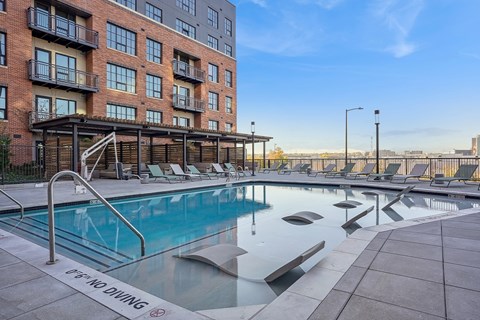 A pool with a diving board in front of a building.