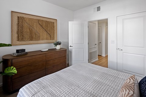 A bedroom with a large bed and a wooden dresser.