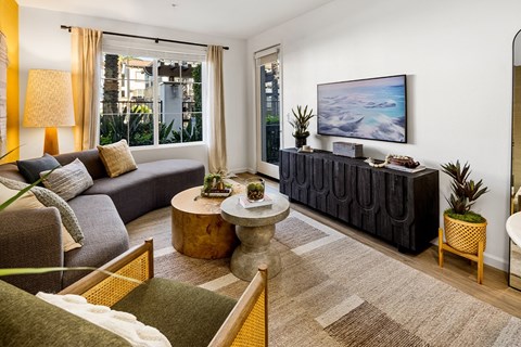 A living room with a grey couch, a wooden table, and a painting on the wall.