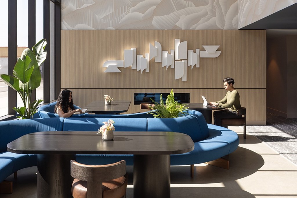 A man and a woman are sitting on a blue couch in a modern lounge area.