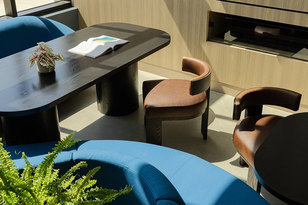 A blue chair sits in front of a table with a plant on it.