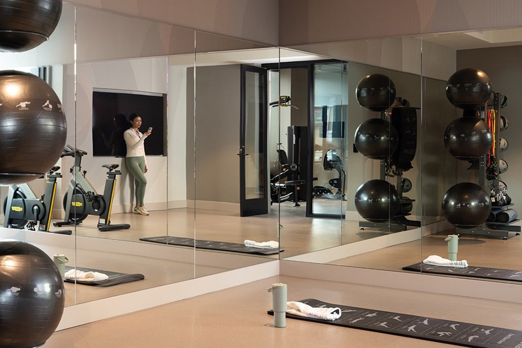 A woman is working out in a gym with a variety of equipment.