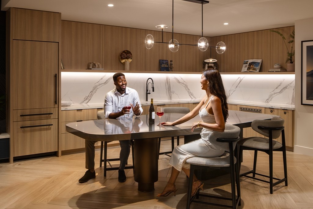 Two people sitting at a table in a modern kitchen.