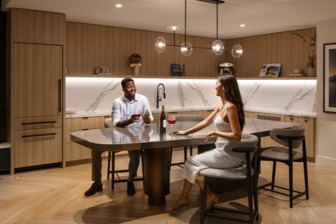 Two people sitting at a table in a modern kitchen.