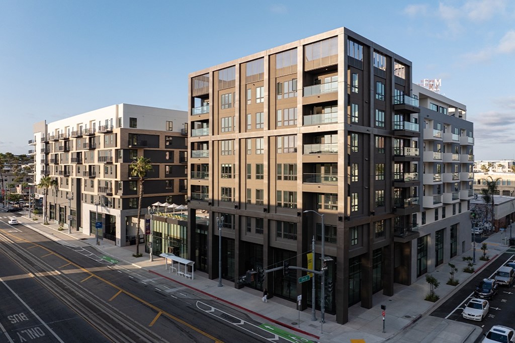A street view of a city with apartment buildings and cars.