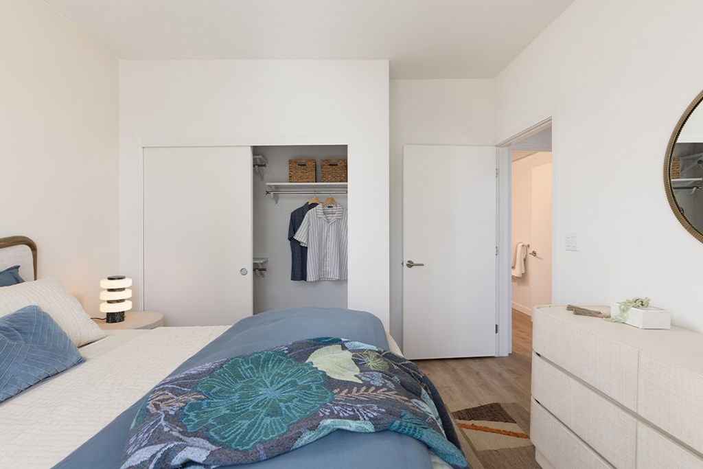 A bedroom with a bed, a dresser, and a mirror.