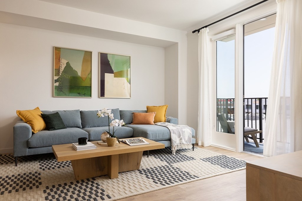 A living room with a blue couch, a coffee table, and two paintings on the wall.