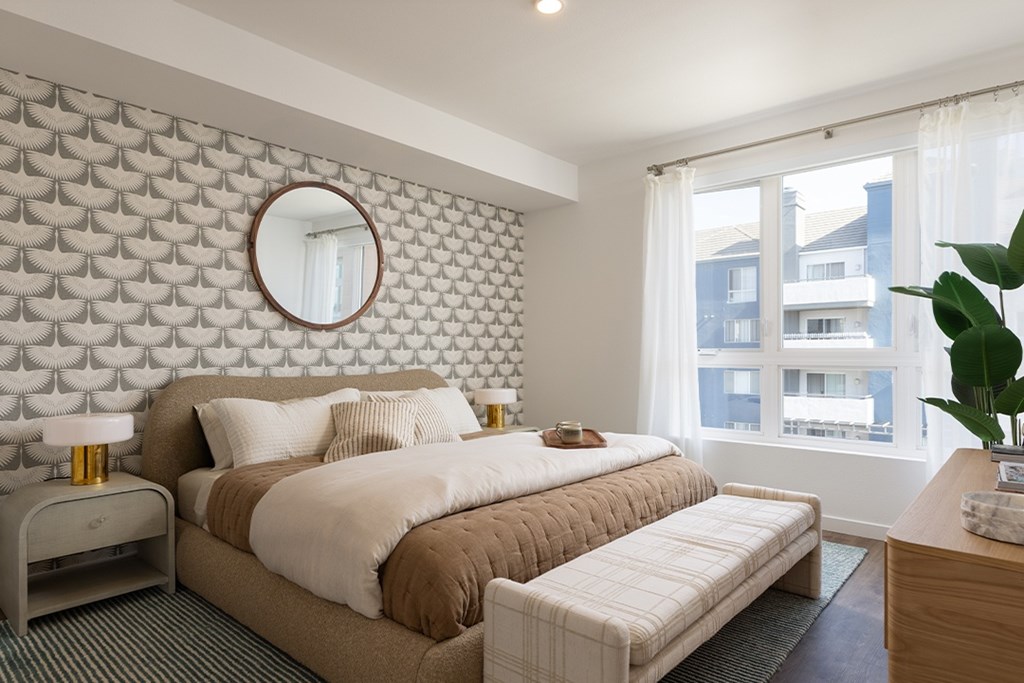A bedroom with a large bed and a round mirror on the wall.