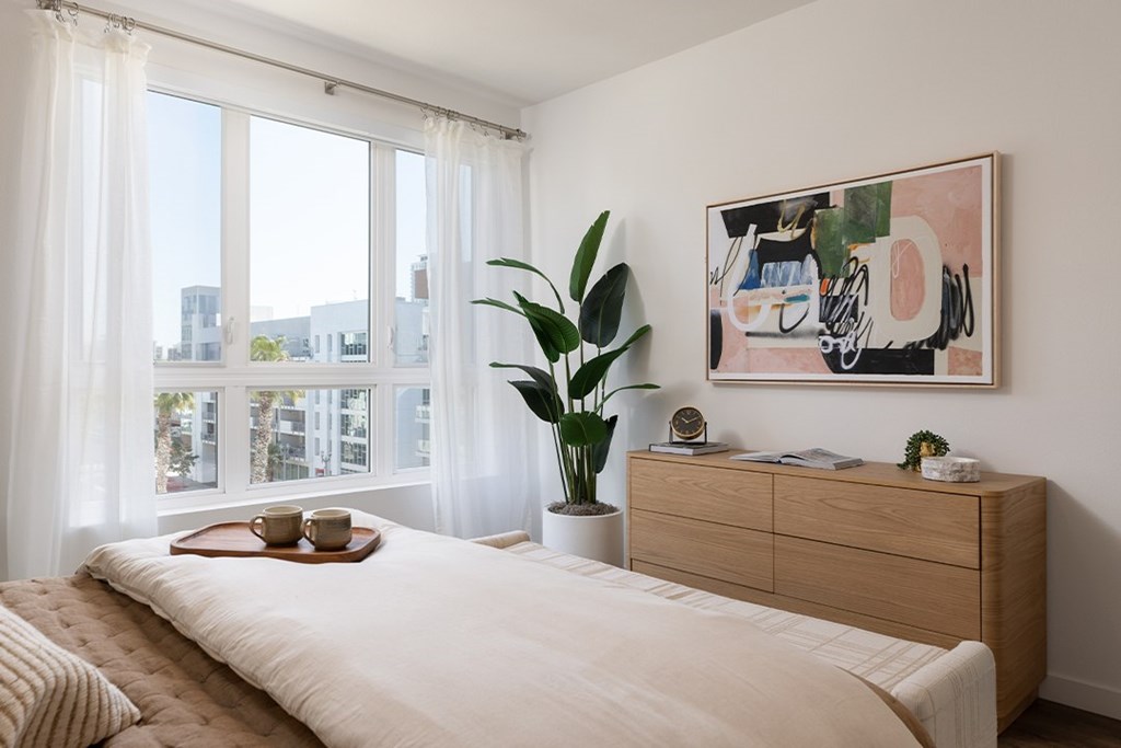 A bedroom with a large bed, a wooden dresser, and a painting on the wall.
