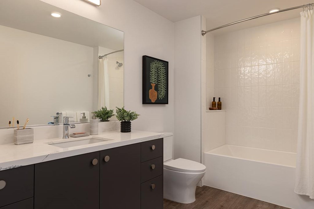 A bathroom with a white tub, sink, and toilet.