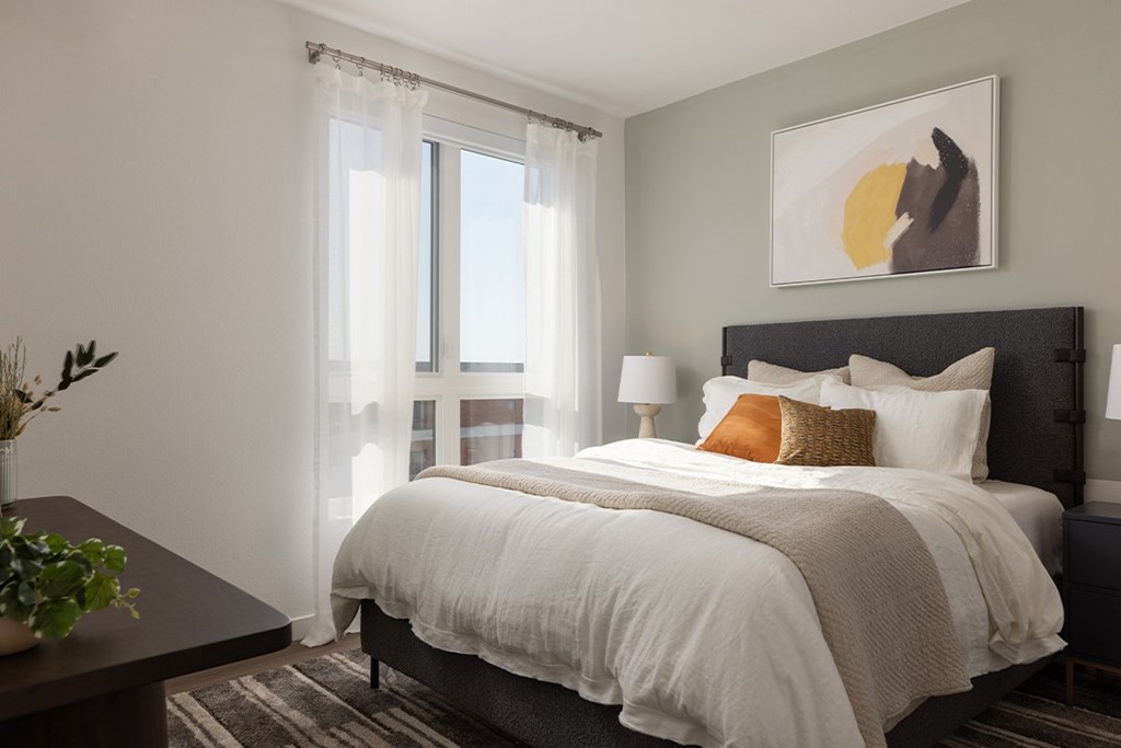 A bedroom with a large bed and a painting above it.