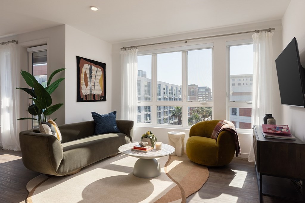 A living room with a couch, a chair, a coffee table, and a flat-screen TV.